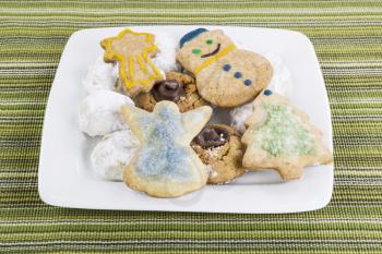 Fresh homemade cookies for the holidays in all shapes and sizes in white plate on green table cloth