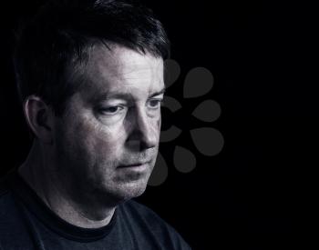 Side view close up of mature man showing negative emotions with dark background 
