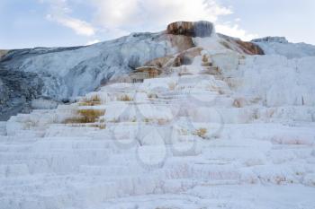 Closeup horizontal image of Mammoth Hot Springs in Northern part of Yellowstone National Park with blue sky and clouds in background