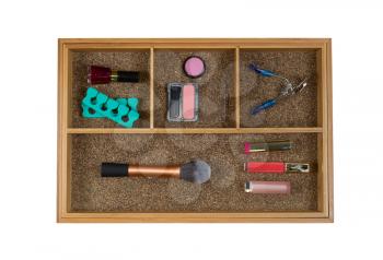 Top view of storage drawer with woman accessories consisting blush, brush, eye lash curler, lip stick, and nail polish isolated on white