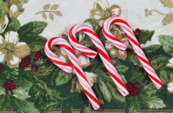 Top view close up of seasonal candy canes placed on holiday table cloth  