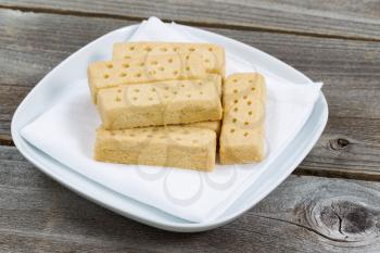 Close up horizontal image of butter cookies on white napkin and plate with rustic wood underneath