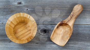 Top view angled shot of an empty wooden bowl and scoop on rustic wood