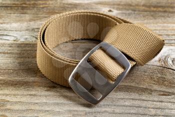 Close up view of a brand new utility belt with large buckle on rustic wooden boards.

