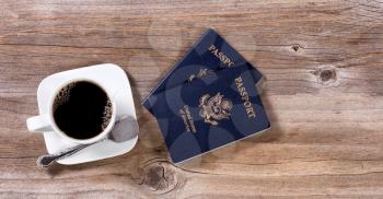 Dark coffee and passports for travel plans on rustic wood. 