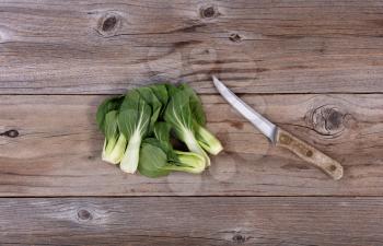 Fresh Chinese Bok Choy and paring knife on rustic wood in flat lay format