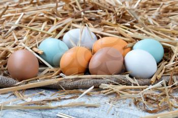 Natural raw eggs resting on straw and burlap with white rustic wood 
