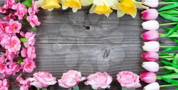 Overhead view of flowers forming a rectangle border on vintage wood for spring time