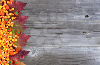 Left border of Halloween candy and Autumn leaves on rustic wooden boards