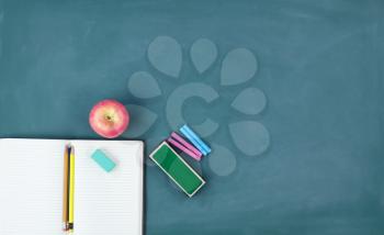 Back to school concept with writing supplies on a green chalkboard 