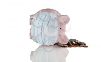 Tipped over piggy bank wearing medical mask and loose coins. Financial crisis concept. Isolated on white with reflection. 