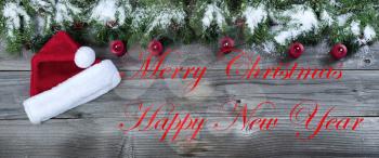 Merry Christmas and happy new concept on rustic natural wooden background with traditional holiday decorations of candles and Santa cap   