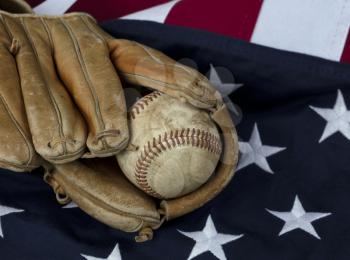 Vintage leather baseball in old glove with American flag in background 