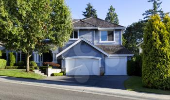 Curb view of a modern home with cedar shake roof during summer morning 