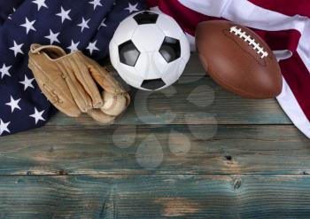 United States flag with soccer ball, baseball and football on faded blue wooden planks for multiple sport concept 