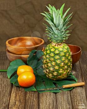 Still Life with Pineapple and Oranges on Wooden background. Closeup.
