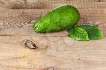 Ripe Green Avocado with Leaves on Wooden Background. Closeup.