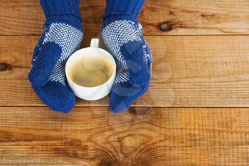 Woman hands in teal gloves are holding a mug with hot coffee or cocoa.  Winter and Christmas concept.