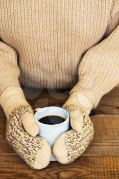 Woman hands in teal gloves are holding a mug with hot coffee or cocoa.  Winter and Christmas concept.