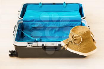 Large family polycarbonate luggage and summer sunny wicker hat on white wooden background. 