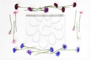 Paper with wreath frame from wildflowers on white background. Overhead view. Flat lay.
