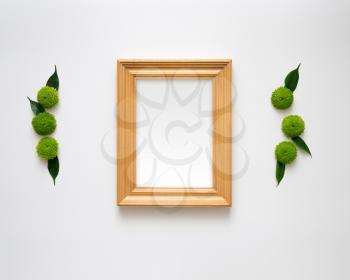 Wooden frame with empty space with decoration of chrysanthemum flowers and ficus leaves on white background. Overhead view. Flat lay.