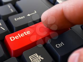 Delete - Written on Red Keyboard Key. Male Hand Presses Button on Black PC Keyboard. Closeup View. Blurred Background.