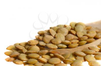  Macro shot of lentils over a wooden spoon on a white background