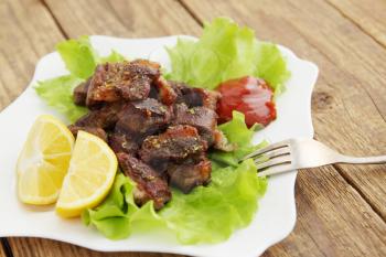 Spicy fried meat with fresh lettuce leaves