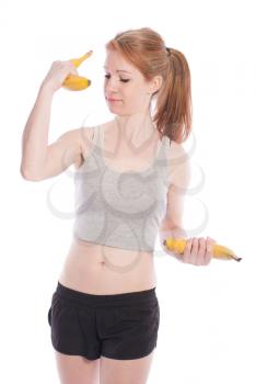 Athletic girl with bananas in hand instead of dumbbells on a white background.