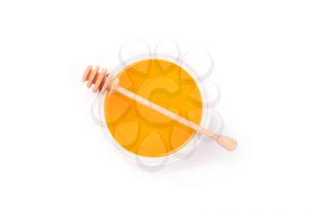 Honey in a bowl and a spoon on a white background.