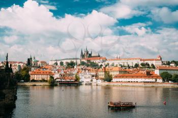 Prague, Czech Republic. Sightseeing Boat Sailing Along Vltava River On Background Upper Town. Prague Castle And Metropolitan Cathedral Of Sts Vitus, Wenceslaus And Adalbert. UNESCO World Heritage Site