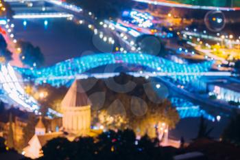 Tbilisi, Georgia. Abstract Blurred Bokeh Architectural Urban Backdrop Of Sioni Cathedral And Bridge Of Peace At Evening Night Street Illumination. Real Colorful Boke Background Defocused Glowing Lights