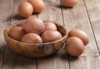 eggs in a wooden bowl on the table from the old boards