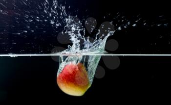 Red apple with splashing water on a black background, movement picture