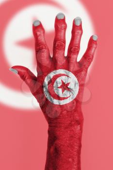 Hand of an old woman wrapped in flag of Tunisia