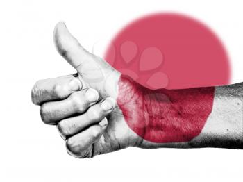 Old woman with arthritis giving the thumbs up sign, wrapped in flag pattern, Japan