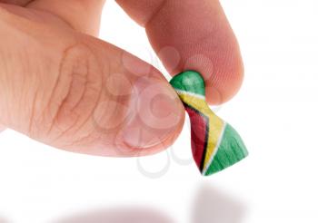 Hand holding wooden pawn with a flag painting, selective focus, Guyana