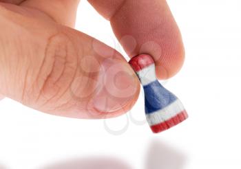 Hand holding wooden pawn with a flag painting, selective focus, Thailand