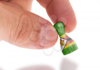 Hand holding wooden pawn with a flag painting, selective focus, Zimbabwe