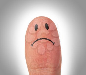 Female thumbs with smile face on the finger, being sad