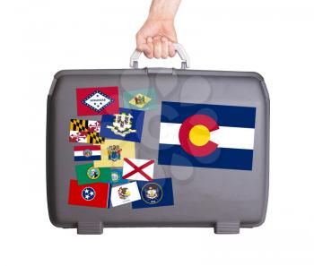 Used plastic suitcase with stains and scratches, stickers of US States, Colorado