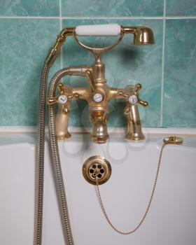 Vintage bath taps, golden tap with a green wall