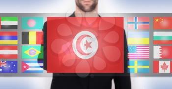 Hand pushing on a touch screen interface, choosing language or country, Tunisia