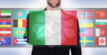 Hand pushing on a touch screen interface, choosing language or country, Italy