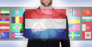 Hand pushing on a touch screen interface, choosing language or country, the Netherlands