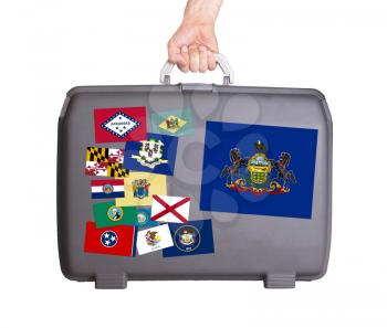 Used plastic suitcase with stains and scratches, stickers of US States, Pennsylvania