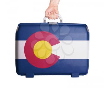 Used plastic suitcase with stains and scratches, printed with flag, Colorado