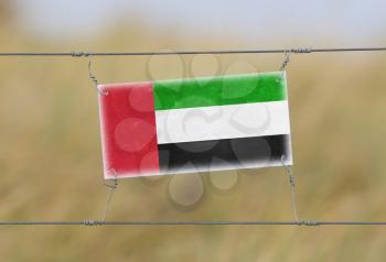 Border fence - Old plastic sign with a flag - United Arab Emirates