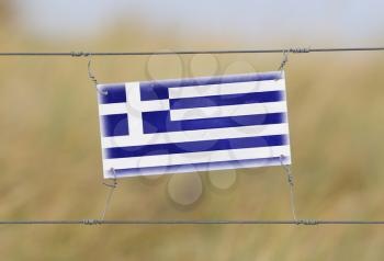 Border fence - Old plastic sign with a flag - Greece